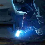 A person welding where the light from the welding is seen